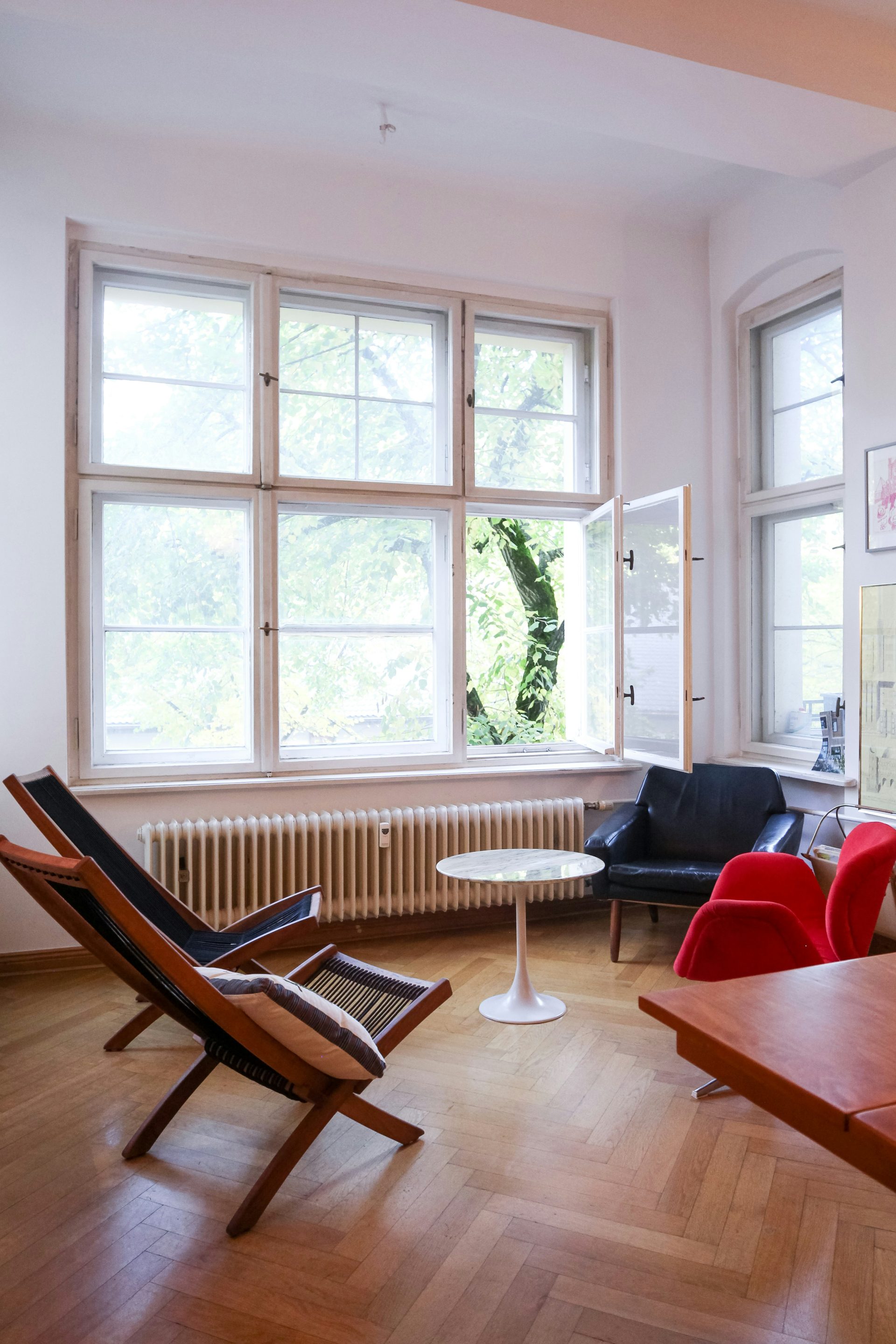 Rot gepolsterter Sessel mit braunem Holzrahmen neben einem Glasfenster mit weißem Holzrahmen