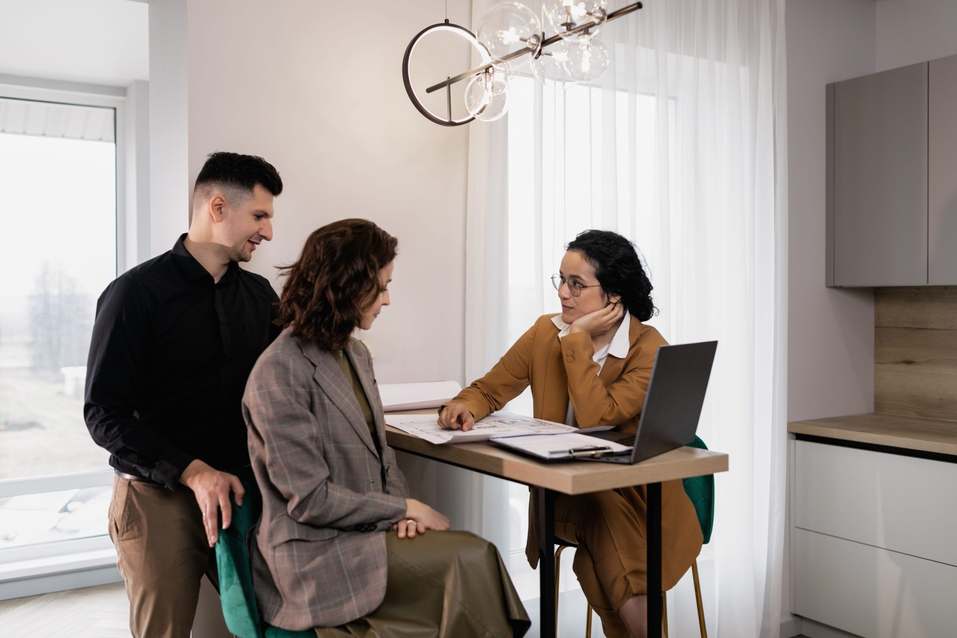 Ein Paar berät sich mit einem Immobilienmakler in einem modernen Büro.